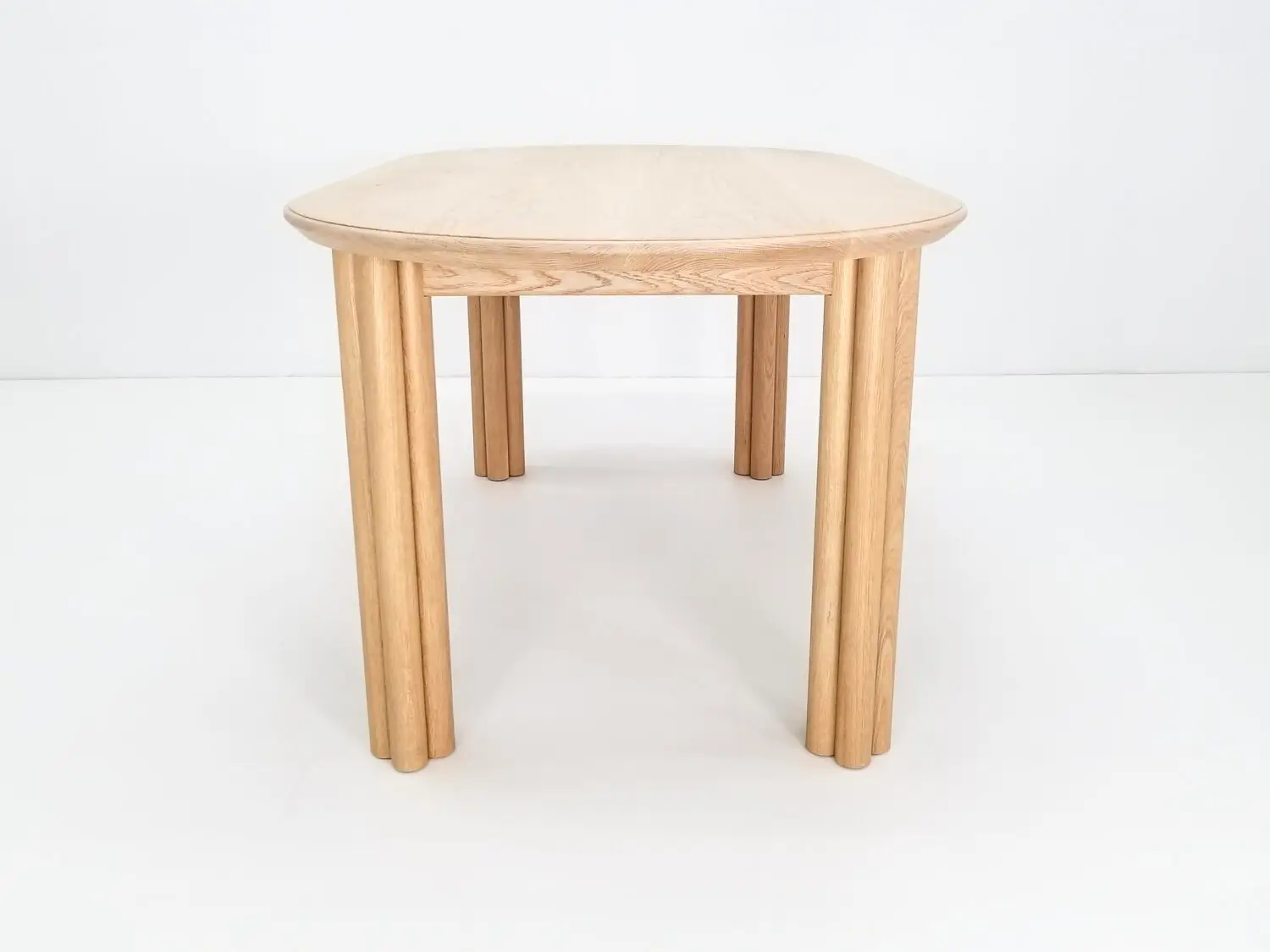 BEAU dining table in natural white oak with a 1⅜ inch thick oval top and clustered cylinder legs