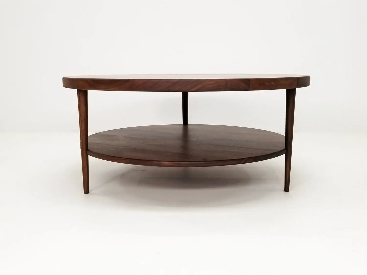 Handcrafted walnut coffee table featuring a 1⅜ inch thick round top with a smooth finish