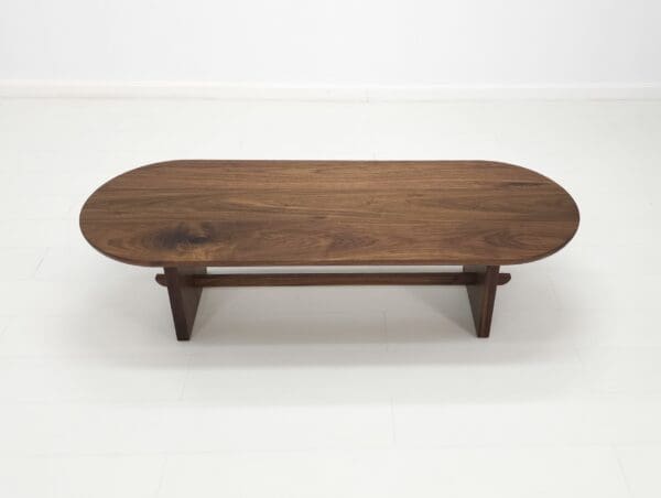 A solid walnut trestle coffee table.