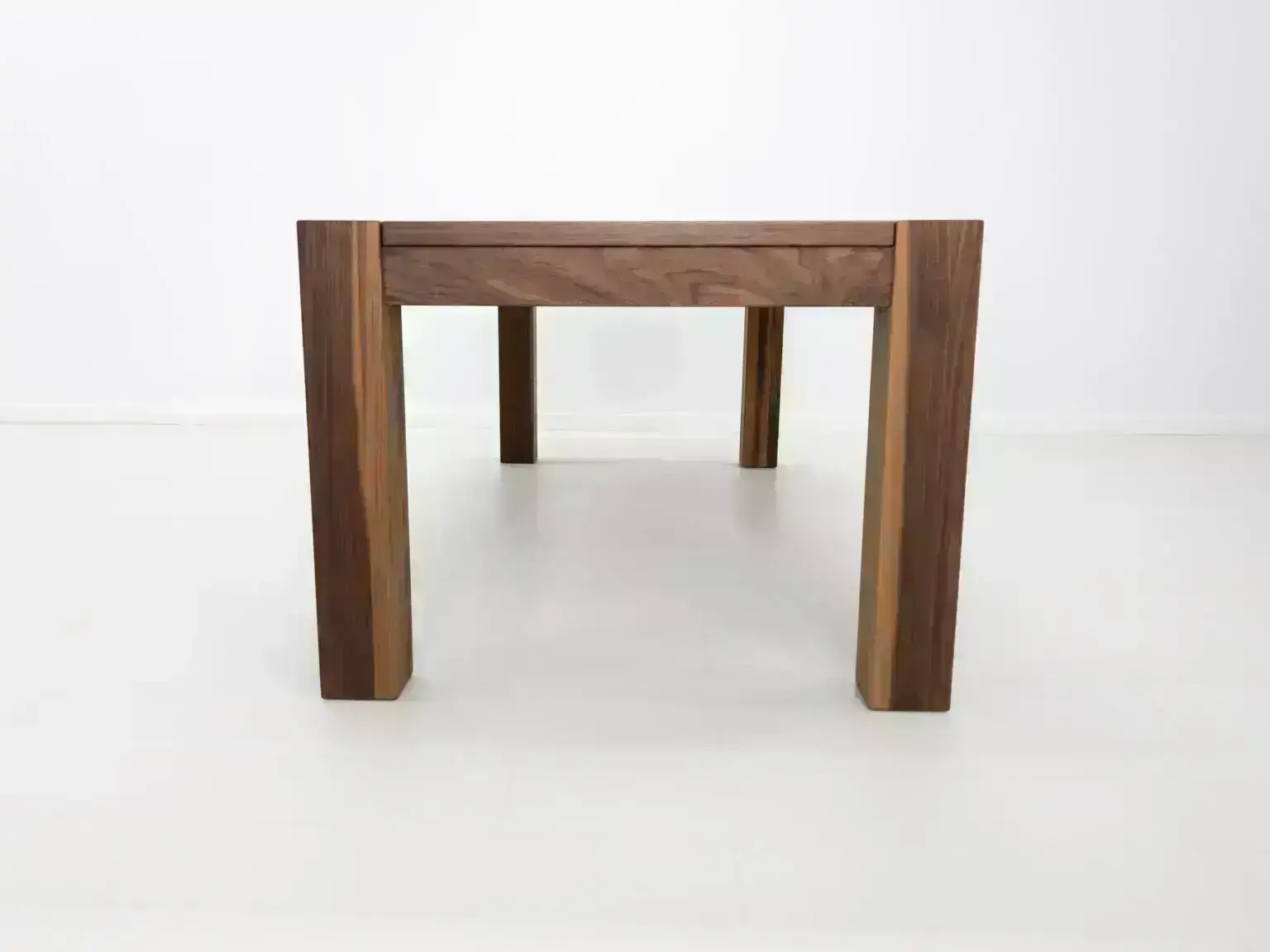 Close up of the JAQI dining table in walnut highlighting its natural wood tones and end grain details