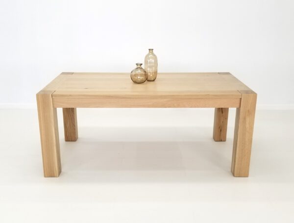 A JAQI Colossal Leg Parsons Dining Table with a vase on top.
