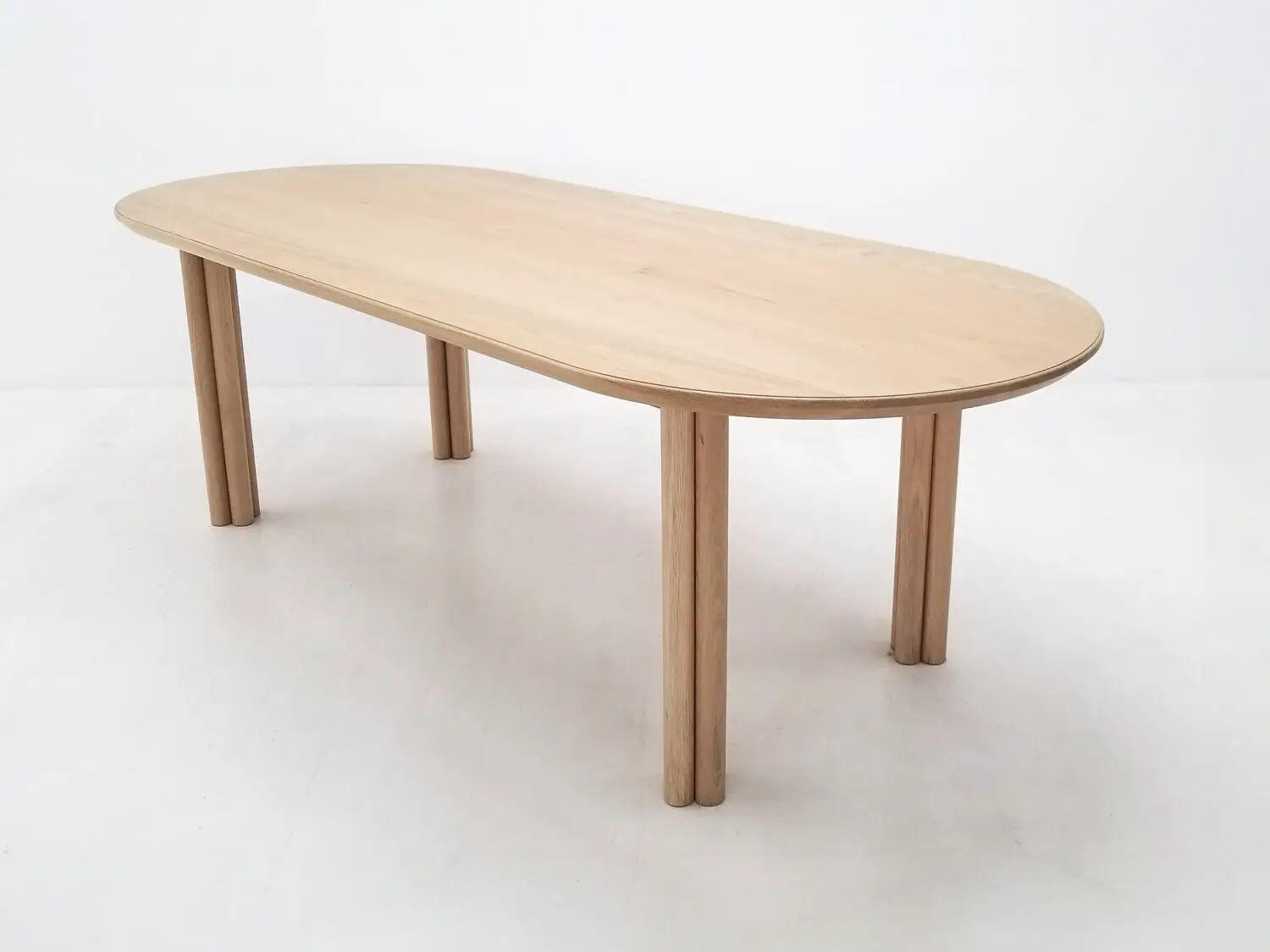 BEAU dining table in natural white oak with a 1⅜ inch thick oval top and clustered cylinder legs