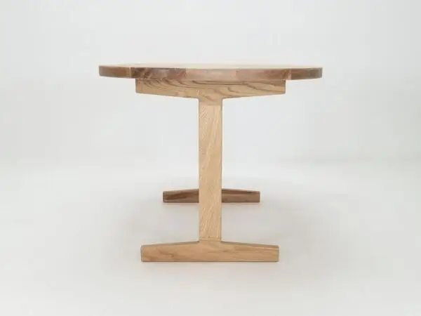 A oval top trestle dining table with two legs.