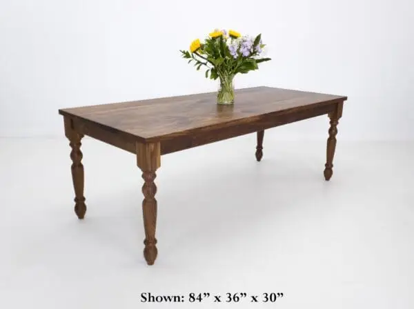 A turned leg dining table with flowers on top of it.