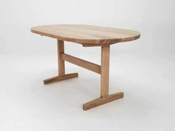 A oval top trestle dining table with two legs.