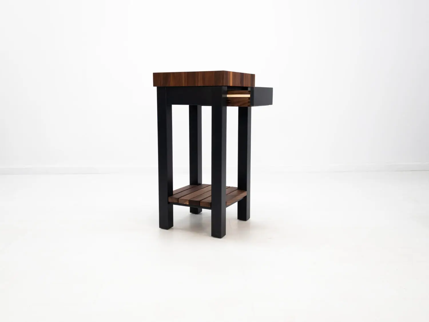 Three quarter view of LUCA island in walnut and black showing end grain butcher block top and slatted shelf