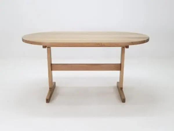 A oval top trestle dining table with two legs.