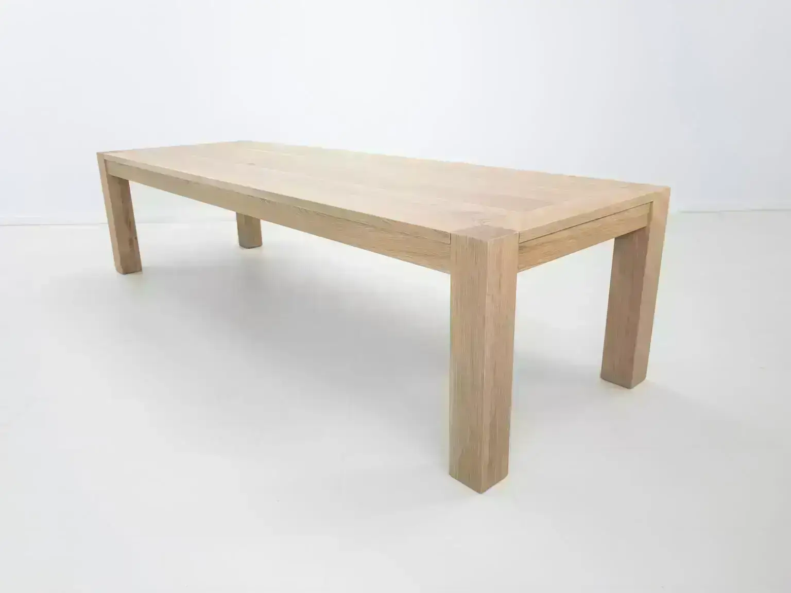 JAQI dining table in seawashed white oak finish featuring a seamless top with breadboard ends