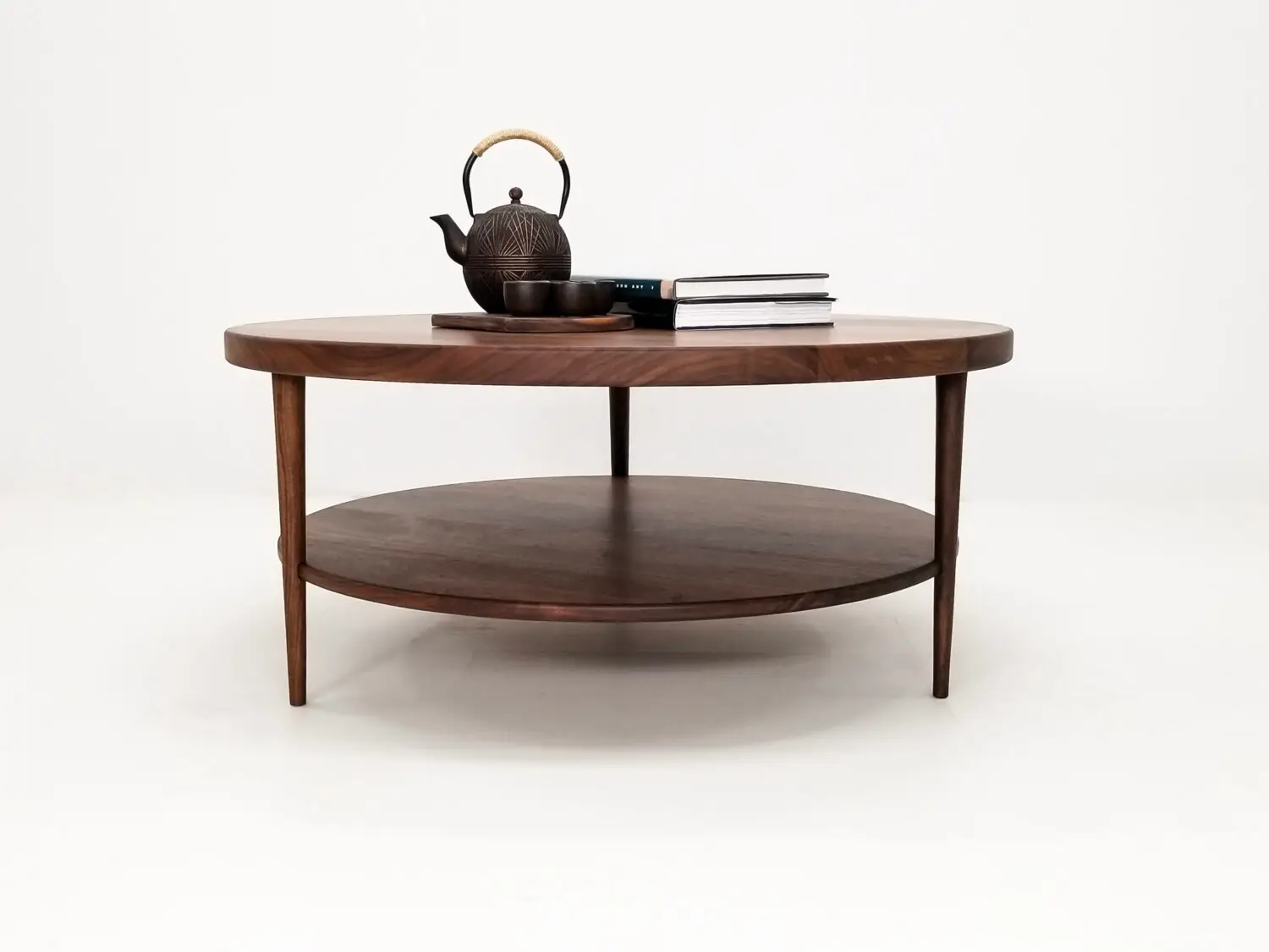 Handcrafted walnut coffee table featuring a 1⅜ inch thick round top with a smooth finish