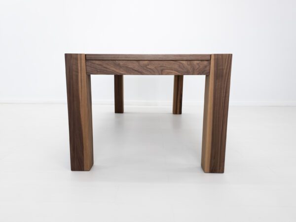 A solid walnut dining table with massive square legs.