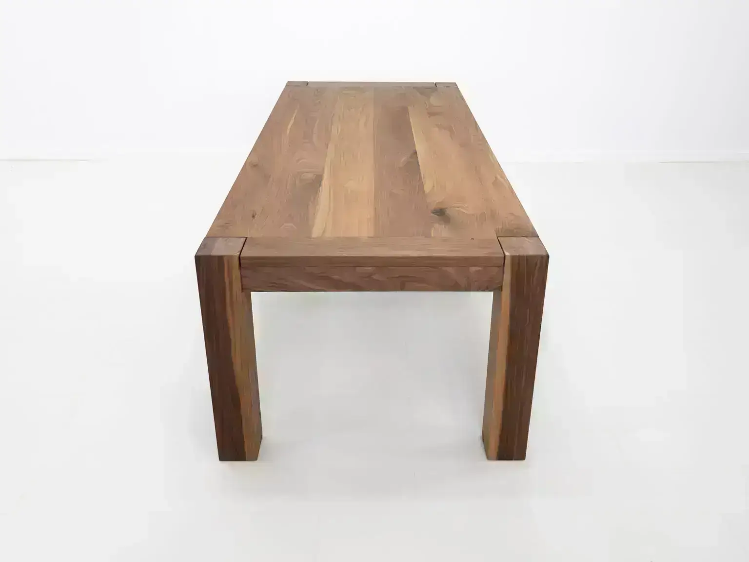 Close up of the JAQI dining table in walnut highlighting its natural wood tones and end grain details