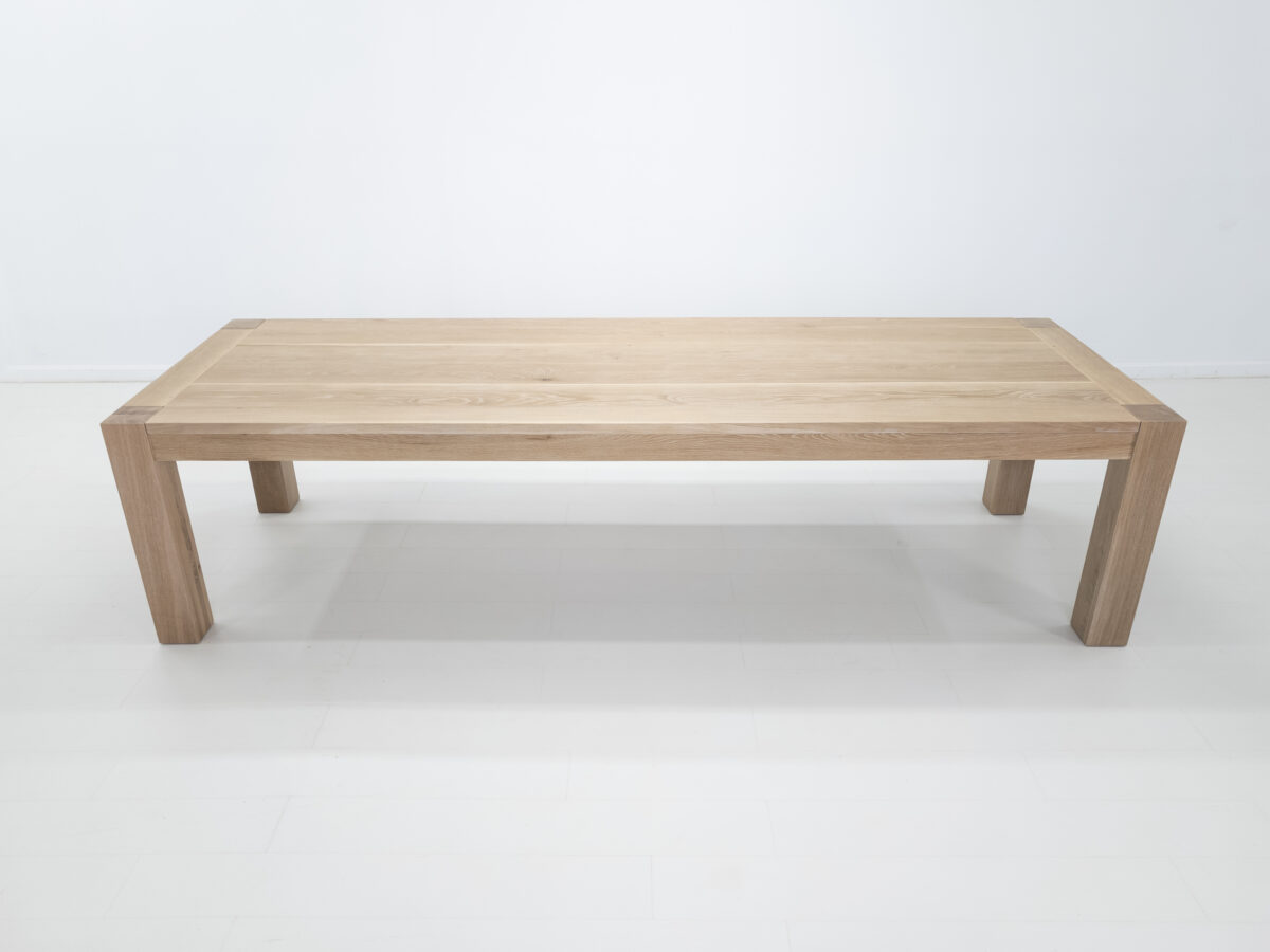 JAQI dining table in seawashed white oak finish featuring a seamless top with breadboard ends