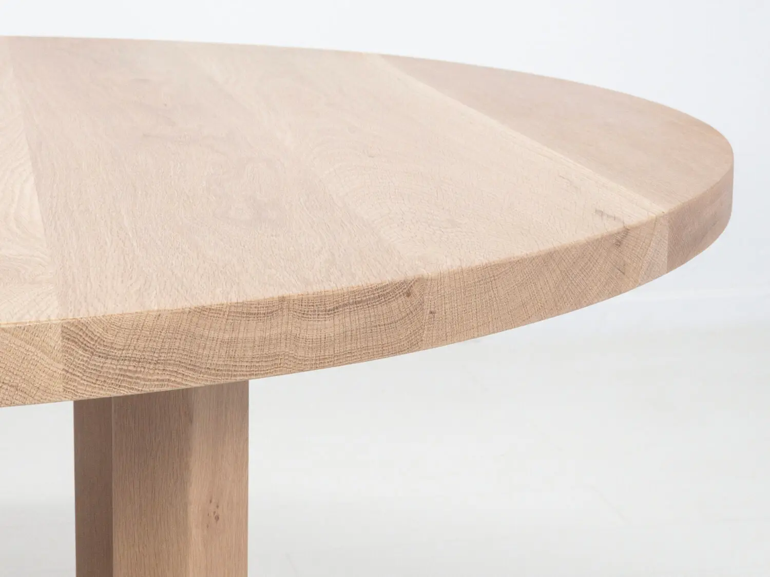 Close up of OTTO dining tables thick round top showcasing premium hardwood grain