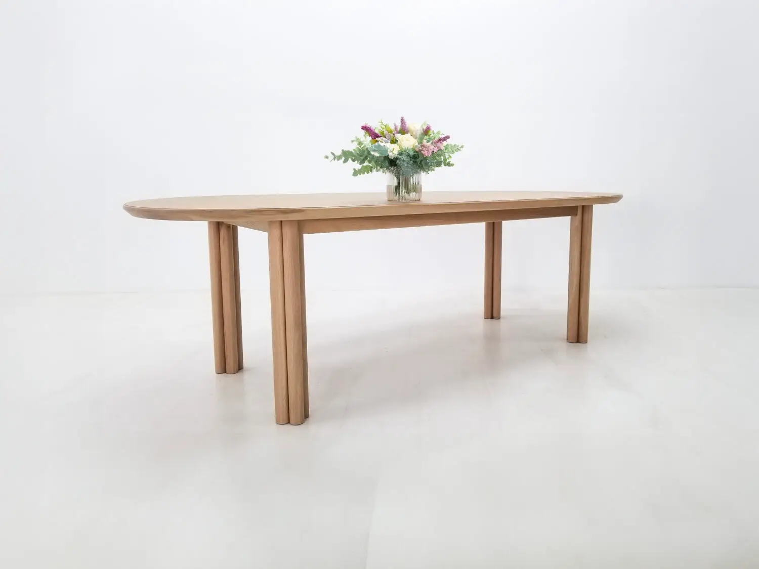 BEAU dining table in natural white oak with a 1⅜ inch thick oval top and clustered cylinder legs