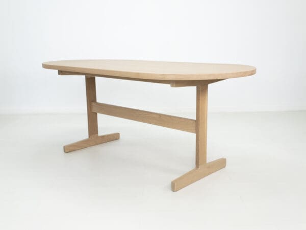 A oval top trestle dining table with two legs.