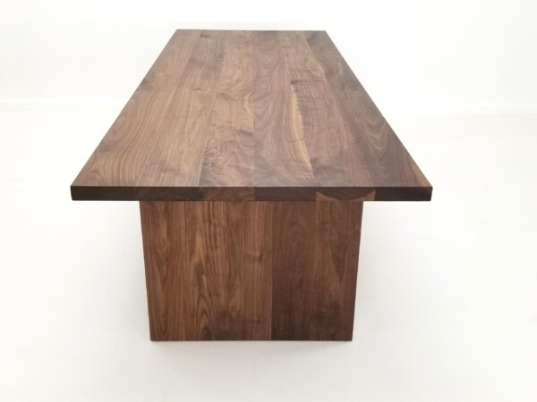 A close up of a large 2" thick walnut dining table.