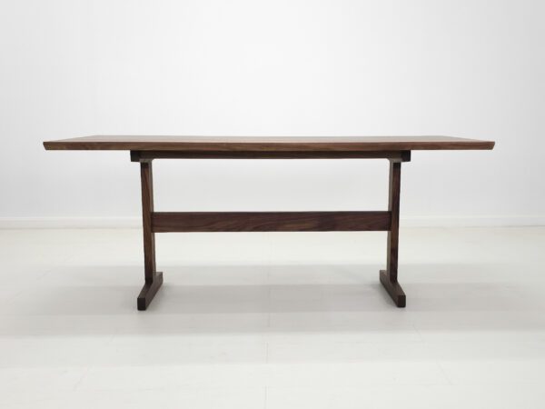 A small walnut trestle dining table.