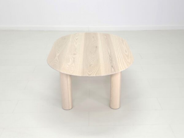 A COVE Coffee Table with two legs in a white room.