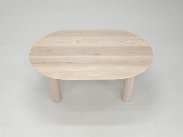 A round COVE Coffee Table with two legs on a white floor.
