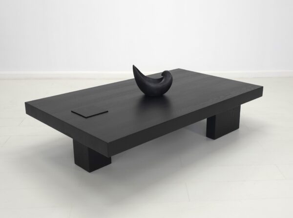 A unique black coffee table with a vase on top.