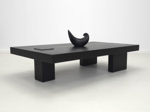 A unique black coffee table with a vase on top.