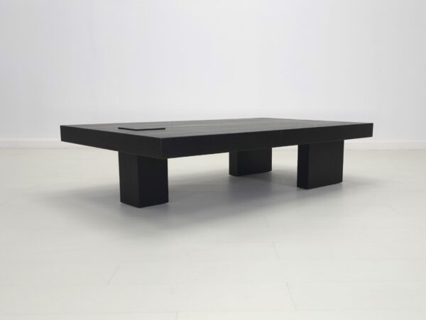 A unique black coffee table with three legs.