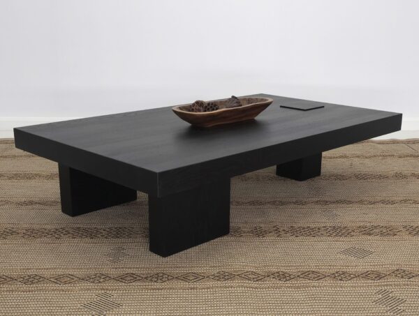 A unique black coffee table on a rug.