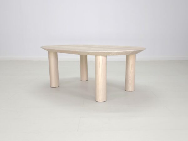 A COVE Coffee Table with two legs on a white floor.