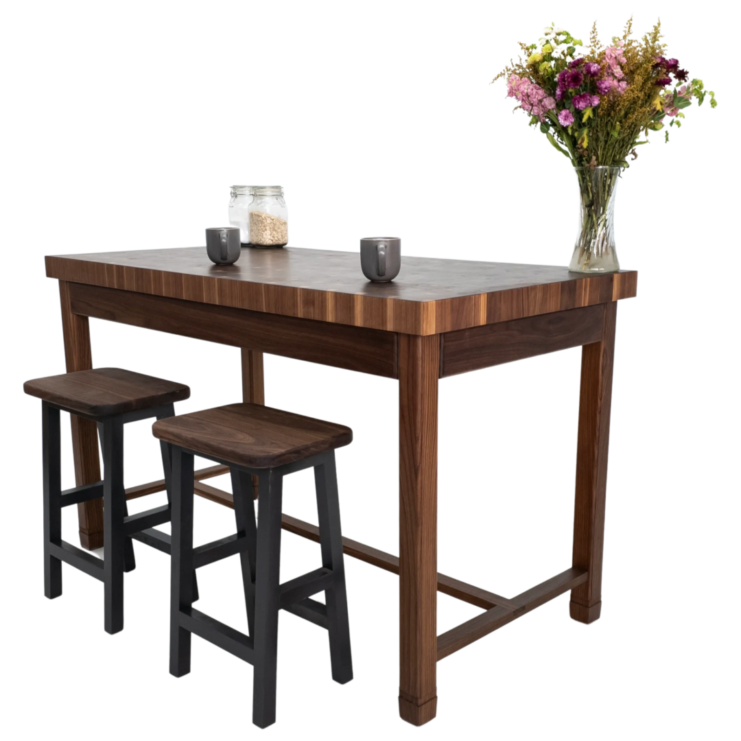 A wooden table with two stools and a vase of flowers on it.