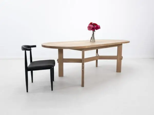 A white oak dining table with an angular stretcher design.