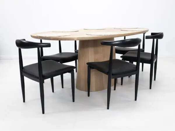 Wooden oval table with black chairs.