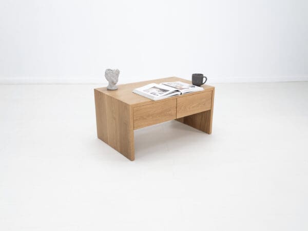 A continuous grain coffee table with drawers and decor on top of it.