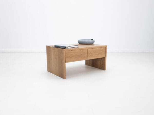 A continuous grain coffee table with drawers and decor on top of it.