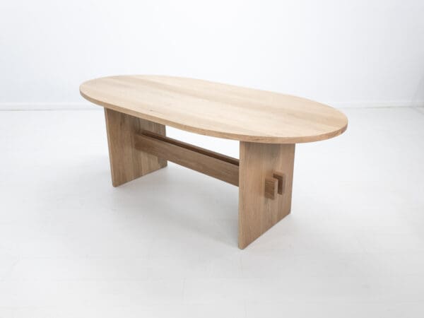 A double stretcher white oak trestle table with an oval top.