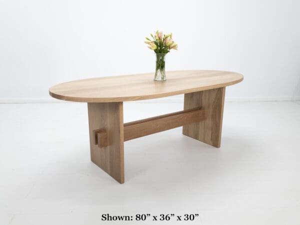 A white oak double stretcher trestle table with decor on top of it.