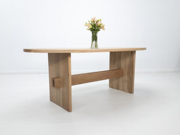 A white oak double stretcher trestle table with decor on top of it.