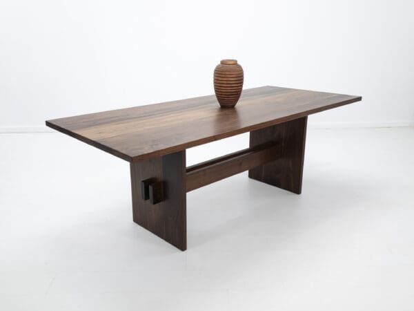 A walnut double stretcher trestle table with decor on top of it.