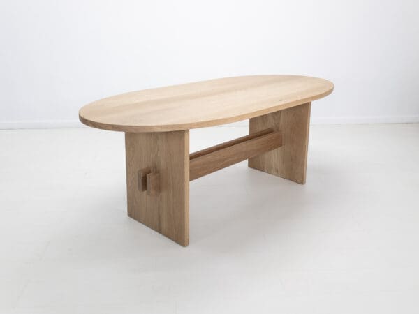 A double stretcher white oak trestle table with an oval top.