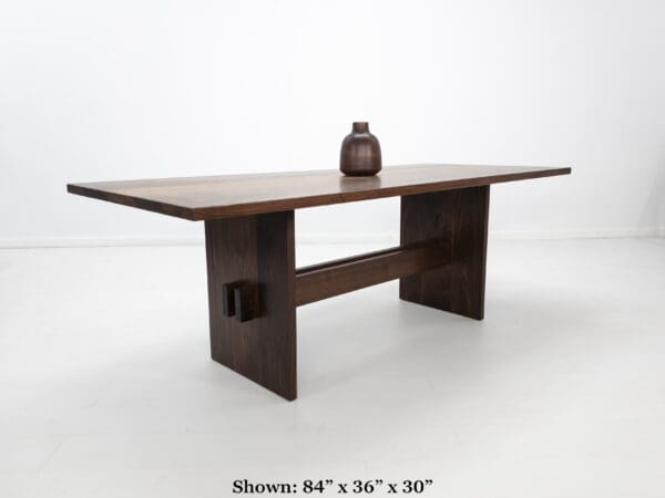 A walnut double stretcher trestle table with decor on top of it.