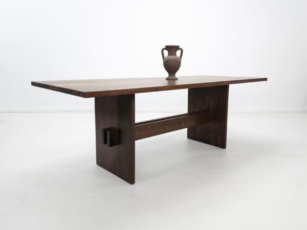 A walnut double stretcher trestle table with decor on top of it.