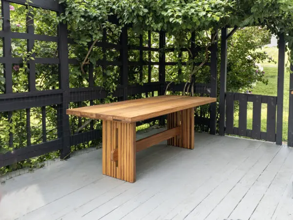 A outdoor table with a a slated top and a trestle base.