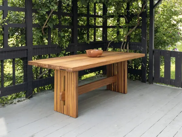 A outdoor table with a a slated top and a trestle base.