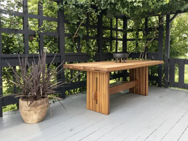 A outdoor table with a a slated top and a trestle base.