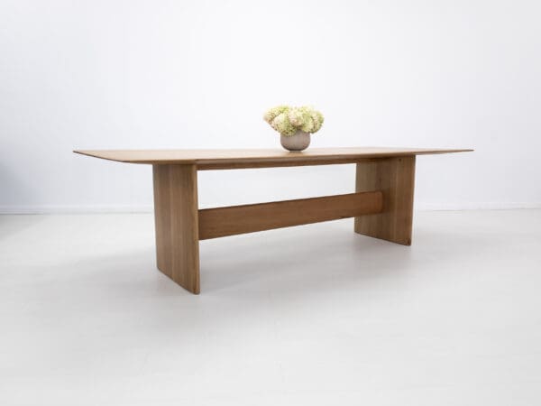 A rift-sawn white oak dining table with a vase on top of it.