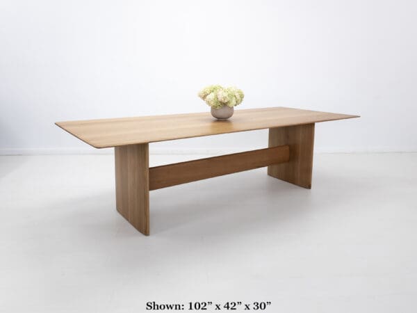 A rift-sawn white oak dining table with a vase on top of it.