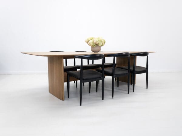 A rift-sawn white oak dining table with decor on top and chairs seated around the table.