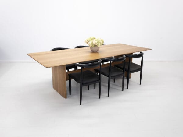 A rift-sawn white oak dining table with decor on top and chairs seated around the table.