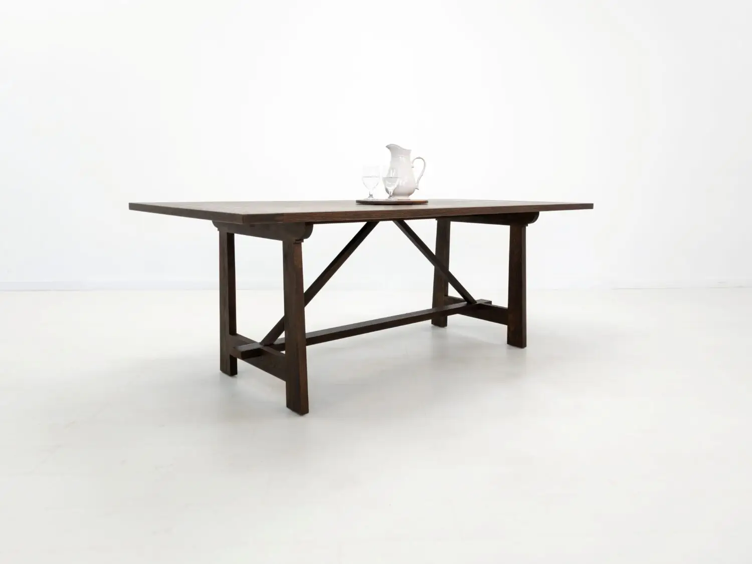 Angled view of the EDEN dining table  Custom white oak dining table in a rich stain featuring a seamless top and structural trestle base