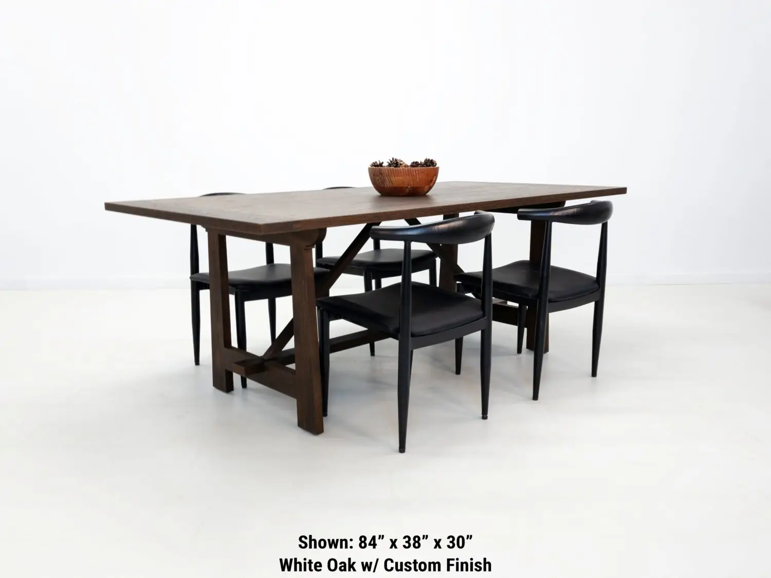 Angled view of the EDEN dining table  Custom white oak dining table in a rich stain featuring a seamless top and structural trestle base