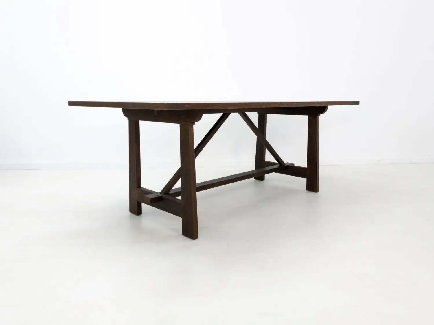 Angled view of the EDEN dining table  Custom white oak dining table in a rich stain featuring a seamless top and structural trestle base